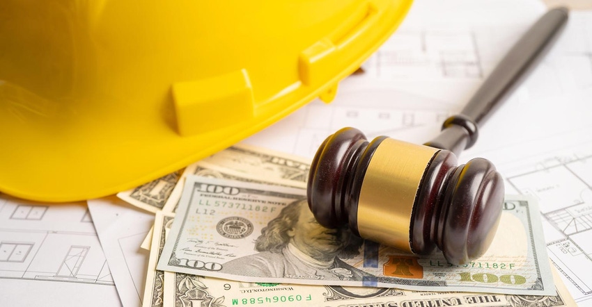 Gavel pictured on top of money and architectural plans with yellow hardhat in background