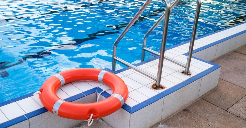 Buoy ring on swimming pool side next to swimming pool ladder, water safety concept