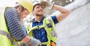 Construction worker fastening coworker’s safety harness