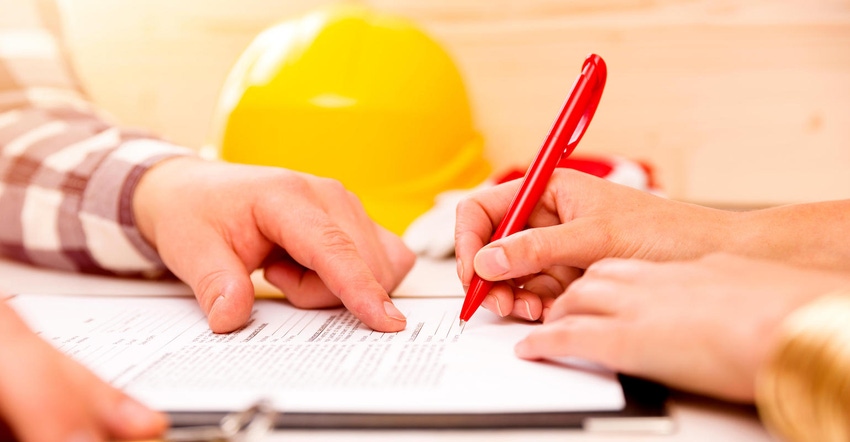 Two hands signing a construction contract