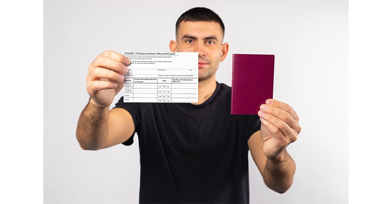 Man with a vaccination card and passport in his hands.