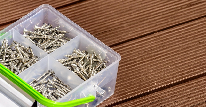 Assorted screws in plastic box on wooden brown deck