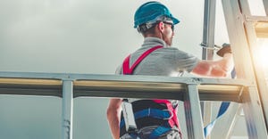 Construction contractor wearing safety harness on steel building frame