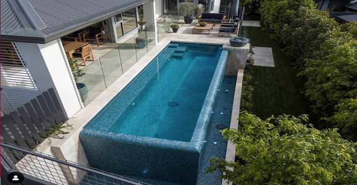 Lead image from Elite Pools of the infinity edge pool with glass railings and a surrounding fountain