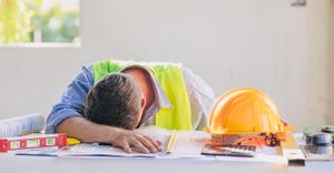 Construction worker sleeping at desk.