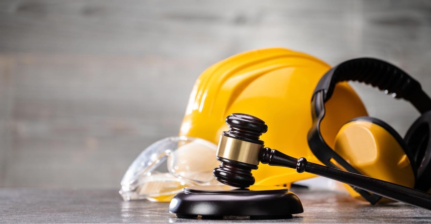 Construction hardhat in yellow with judge's gavel in the foreground