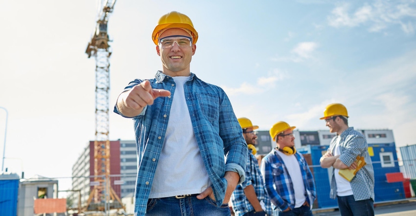 Builders in hard hats standing on construction site with a crane in background