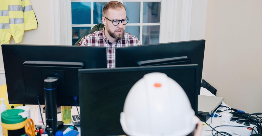 Male building contractor using computer while working in office