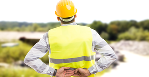 Injured construction worker suffering back pain in lower back area at work.