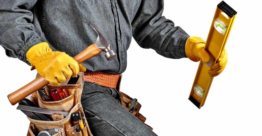 Man wearing used tool belt filled with carpenter tools carrying a yellow level, hardhat and hammer