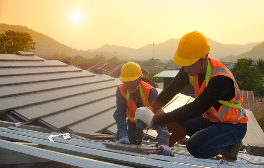 Two workers roofing in the evening or late afternoon
