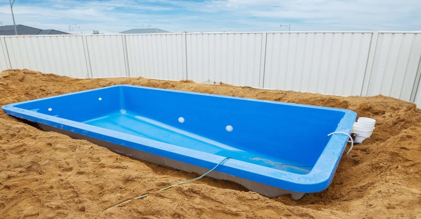 Installation of a plastic fiberglass pool in the ground at house backyard