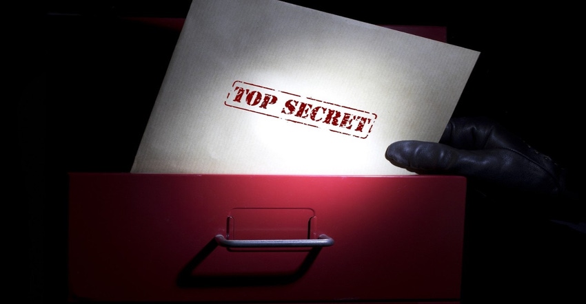 Piece of paper that reads top secret being taken out of a file cabinet by a gloved hand
