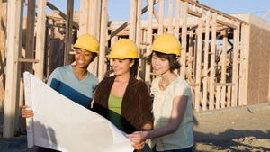 Three women in yellow hard hats on a construction jobsite