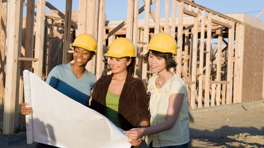 Three women in yellow hard hats on a construction jobsite