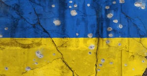 Full frame photo of a weathered flag of Ukraine painted on a cracked wall with bullet holes.