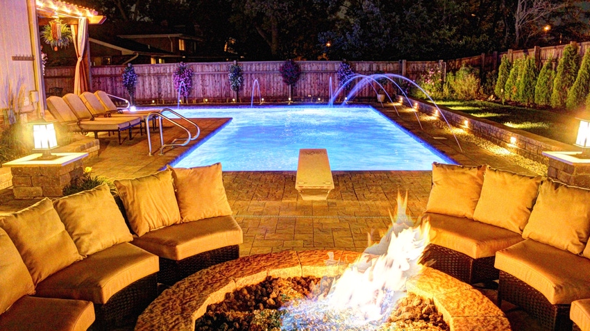 Image of a full backyard at nighttime with an inground pool and fire pit by All Seasons Pool Spa & Outdoor Living