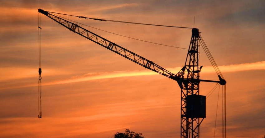 Black silhouette of a construction crane at dusk.