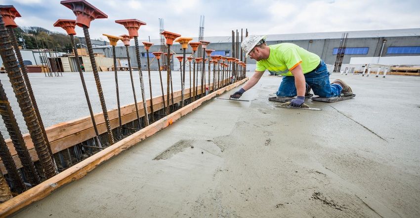 Construction worker spreading concrete on a job site