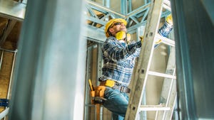 Construction worker wearing safety hard hat and noise reduction headphones climbing a ladder