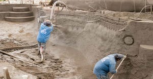 Two laborers Spraying Gunite for Pool Construction in a Backyard