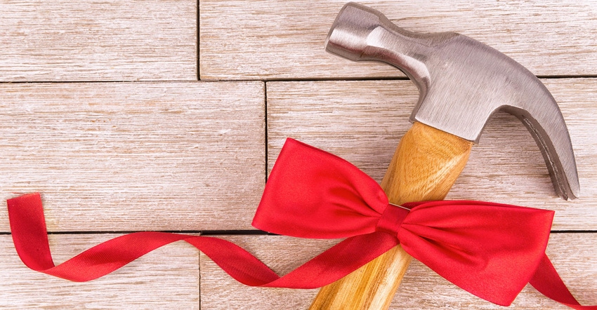 Hammer on a white wooden plank, tied nicely with a red holiday bow