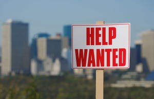 Help wanted sign with city skyline in the background.