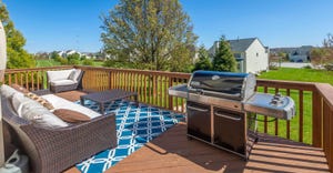 Backyard deck featuring couches, a rug, a grill and a view of green grass and houses