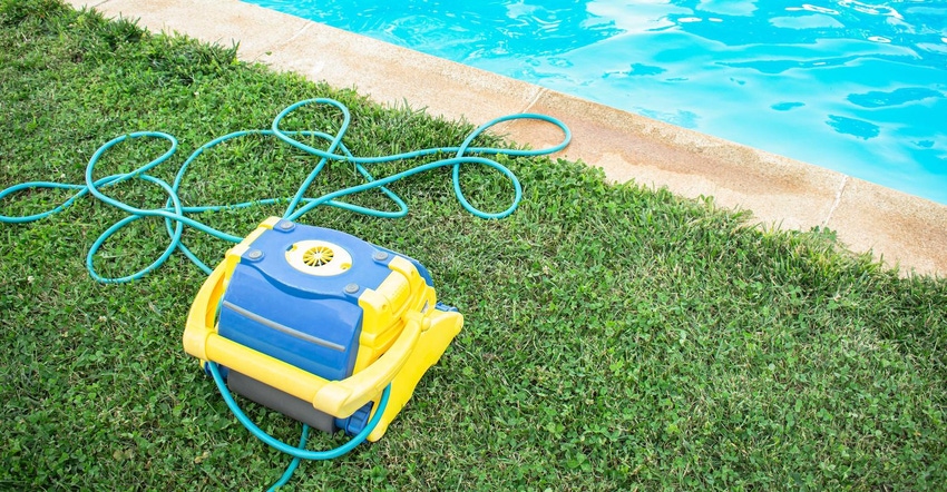 Automatic pool cleaner with electric hose protected on grass and freshly cleaned pool