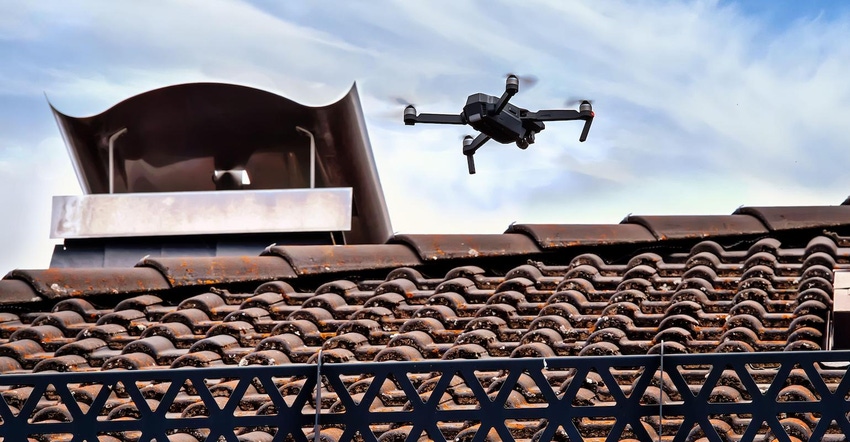 Drone in the air inspecting the roof over the house.