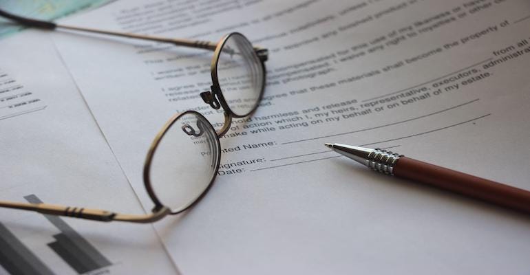Glasses and a pen sitting on top of a generic legal contract