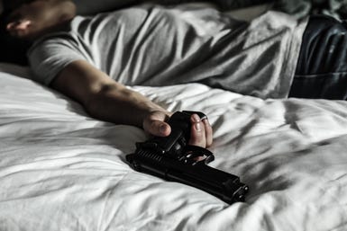 Man laying on bed with a handgun in his hand