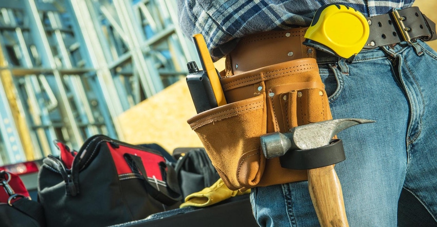 Working construction contractor tool belt closeup featuring hammer, measuring tape and walkie talkie