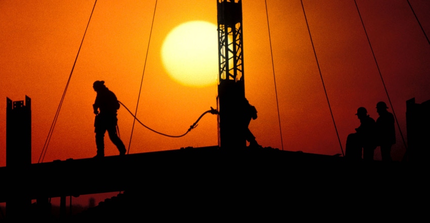 High steel construction workers building office tower at sunset New York City.
