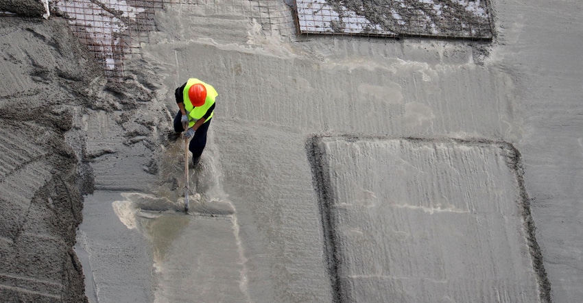 Worker pours concrete at the construction site, view from the top.