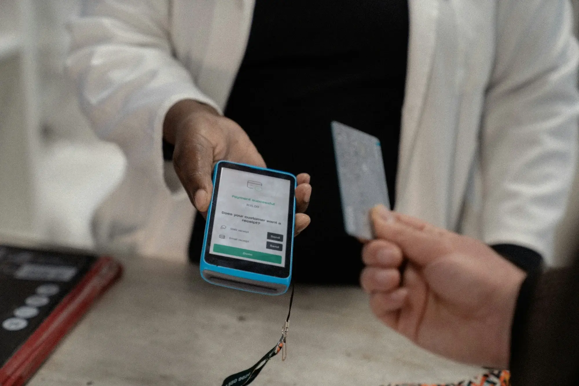 Business owner taking payment at card machine at till in store.