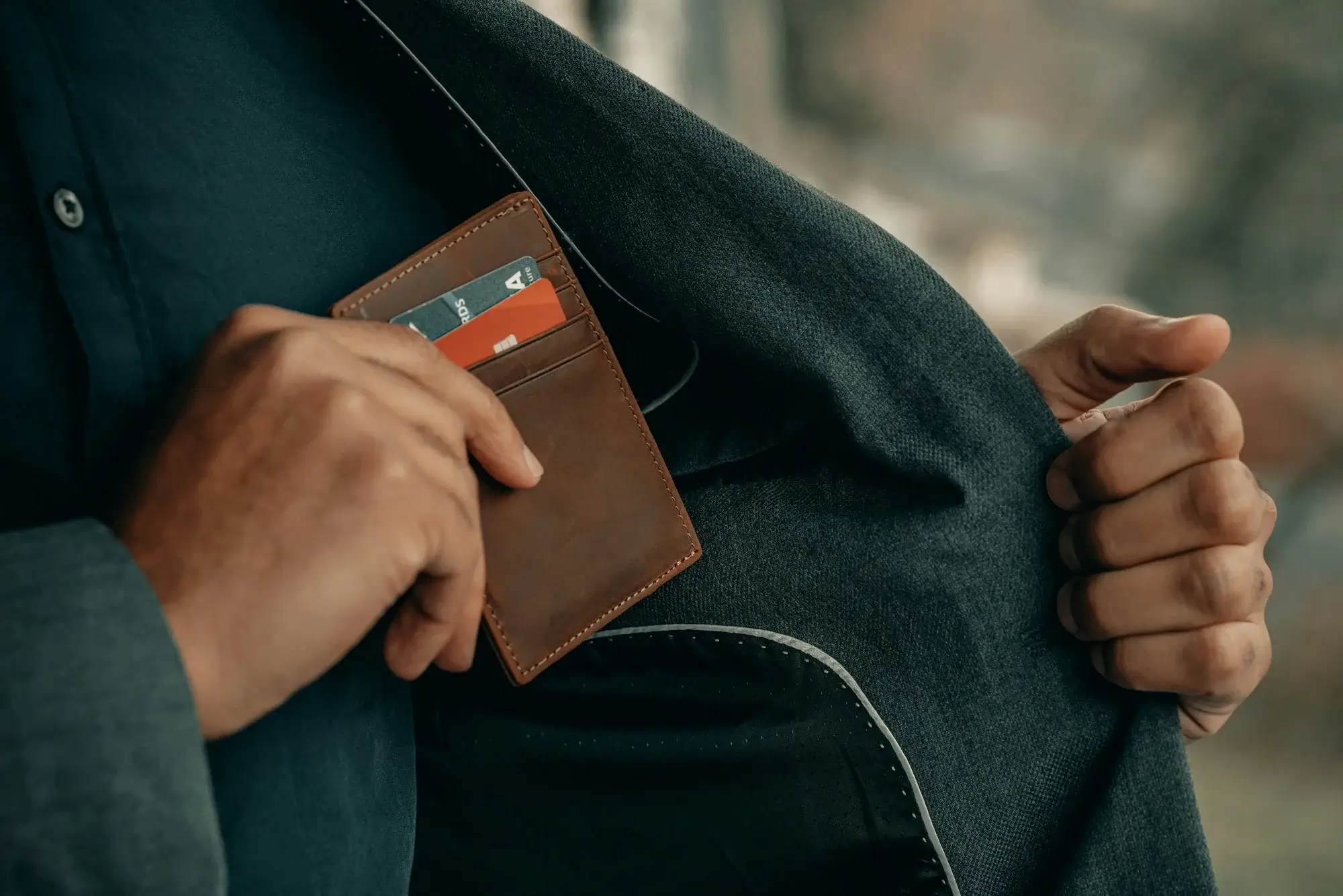 Business owner putting wallet into inside pocket of jacket, with credit card visible. 