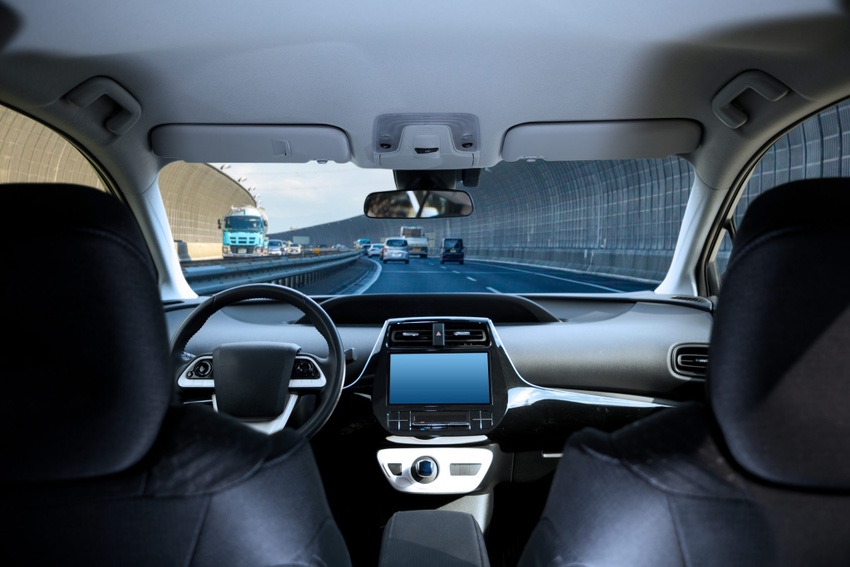Image shows the cockpit of driverless car driving on highway viewed from rear seat. Image shows the cockpit of driverless car driving on highway viewed from rear seat.