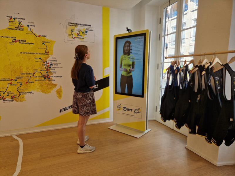 A spectator looking at the Marianne digital human experience kiosk at the 2023 tour de France