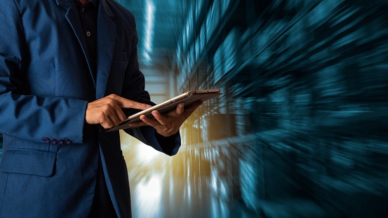 Image shows a businessman manager using tablet check and control for workers with Modern Trade warehouse logistics. Industry Image shows a businessman manager using tablet check and control for workers with Modern Trade warehouse logistics. Industry