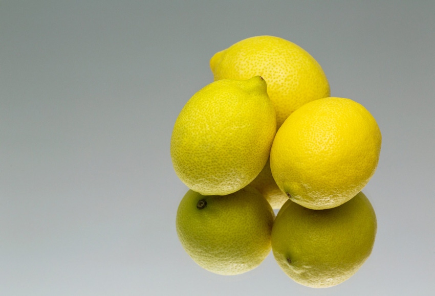 Three lemons on a reflective surface.
