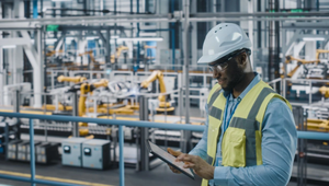 Engineer in high-vis vest uses tablet in automotive industrial facility