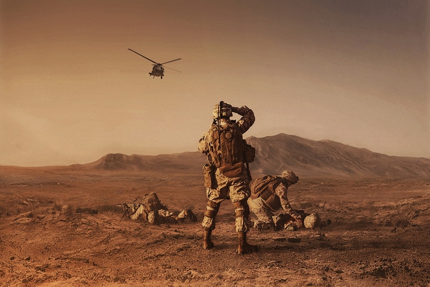 Photo of military personnel on a barren landscape with a helicopter in the air Photo of military personnel on a barren landscape with a helicopter in the air