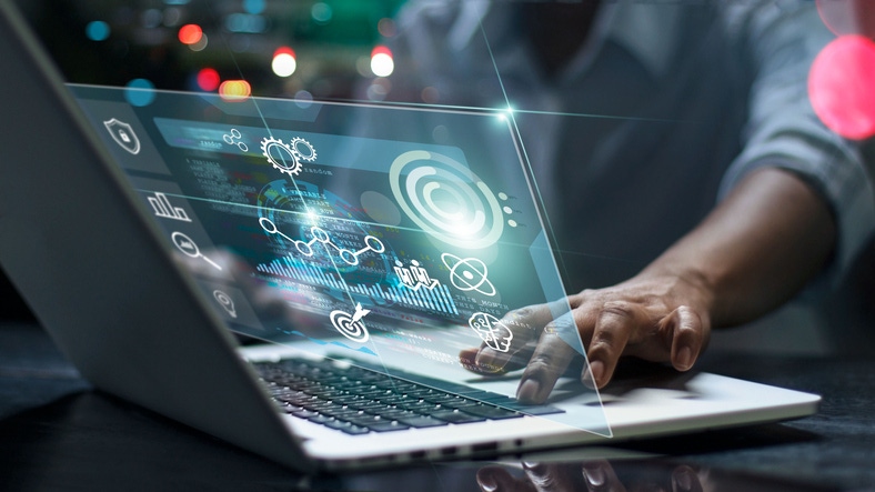 Image shows a male programmer using laptop analyzing and developing in various information on futuristic virtual interface sc Image shows a male programmer using laptop analyzing and developing in various information on futuristic virtual interface sc