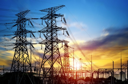 Image shows a high pressure wire tower at sunset at dusk.