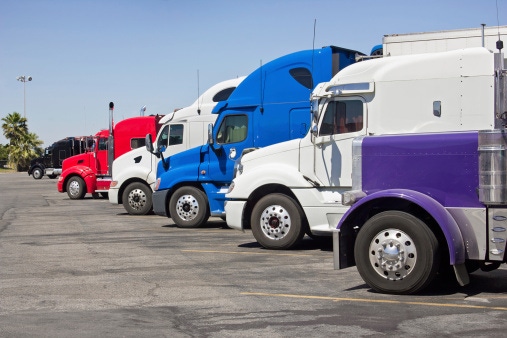 Image shows multiple trucks parked in a large parking lot.