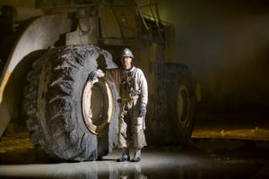 Man standing next to large digger tyre