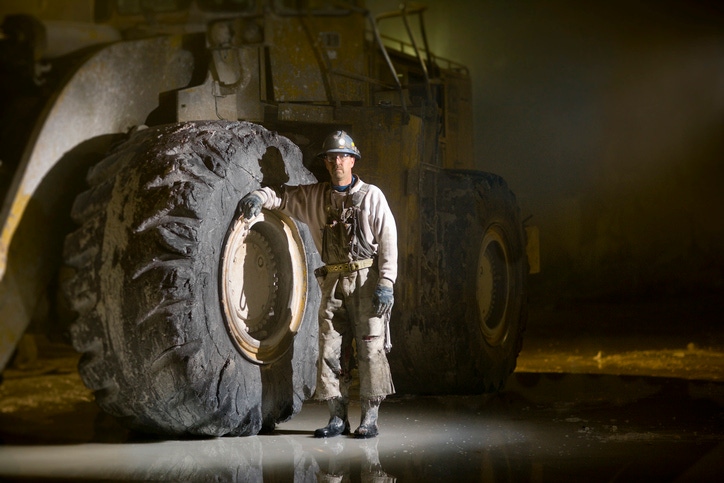 Man standing next to large digger tyre