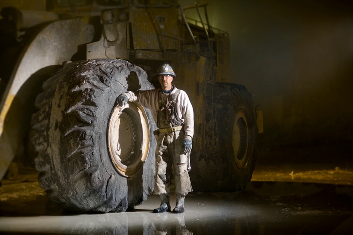 Man standing next to large digger tyre Man standing next to large digger tyre