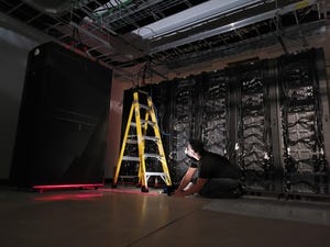 An engineer works with a stepladder on constructing data center racks